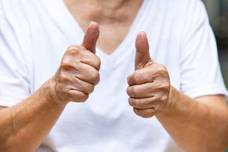 Senior woman's hand  symbol meaning " Good " on white t shirt, Body language conceptの写真素材