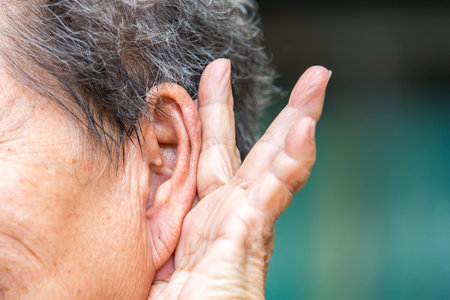 Senior woman holding hand to left ear, trying to listen, Close up