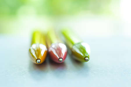 3 colour pens ( Yellow, Pink, Green ) on white paper, Bokeh green garden background, Notebook, Close up & Macro shot, Selective focus, Communication, Stationery conceptの写真素材