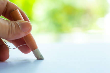 Woman's left Hand holding dermatograph pencil writing letter on white paper, Bokeh green garden background, Notebook, Close up & Macro shot, Selective focus, Communication, Stationery conceptの写真素材