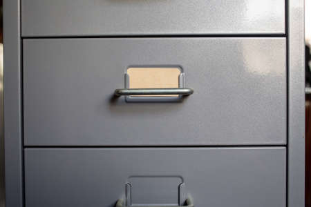Filing cabinet with closed drawer, A brown cards for write letter, Grey silver metal colour, Administration and storage concept, closeup & Macro shotの写真素材