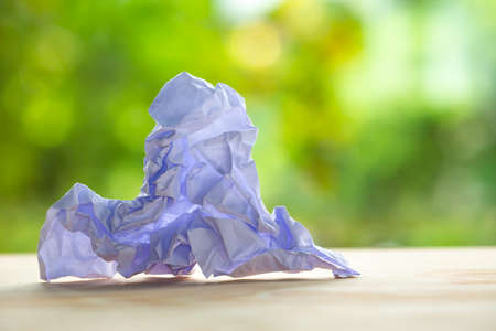 Crumpled white paper on wood table, Bokeh green garden background, Close up & Macro shot, Selective focus, Brainstorming, Creative idea, Business conceptの写真素材