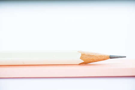 A white pencil on pink and white notebook on white background, Close up & Macro shot, Selective focus, Stationery conceptの写真素材