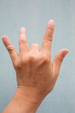 Trigger Finger lock on middle finger of woman's back left hand, Suffering from pain, On Blue-grey colour background,  Close up & Macro shot, Office syndrome, Health care conceptの写真素材