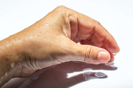 Woman's wet side hand with water drops on white acrylic background, Close up & Macro shot, Selective focus, Asian Body skin part,  Relaxing Bath, Healthcare conceptの写真素材