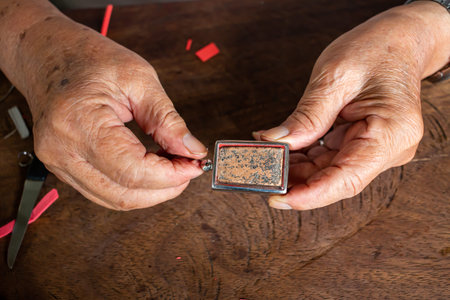 Senior man' s hands to provide Amulet, Small Buddha image with a metal cap on wood table texture...