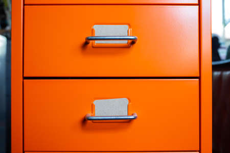 Filing cabinet with closed drawer, 2 brown cards for write letter, Orange metal colour, Administration and storage concept, closeup & Macro shotの写真素材