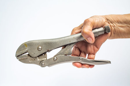 Senior Woman's right hand holding silver metal pliers on white background, Construction building and...