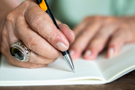 Senior man's hand writing letter on ivory color paper, Notebook,  A black mix silver pen, On wooden...