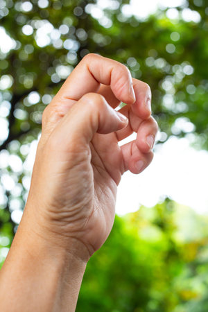 Trigger Finger lock on fingers of woman's side left hand, Suffering from pain, in bokeh green garden...