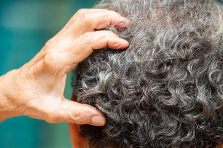 Senior woman scratching back head, thinking about something, Grey curly hair, Close up, Body conceptの写真素材