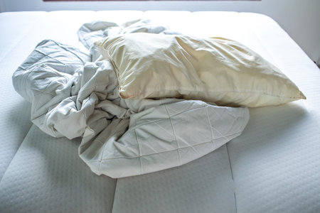 White crumpled bed sheet, Ivory pillow on white bed, Close up shot, Selective focus, Bedroom...