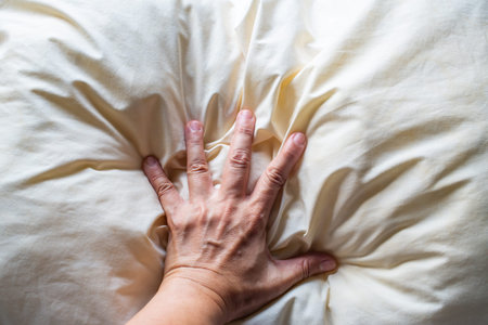 Woman's hand squeezing ivory pillow, Close up and macro shot, Selective focus, Bedroom conceptの写真素材