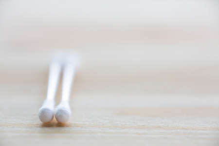 Two white plastic cotton buds on wood table texture background, Close up & Macro shot, Selective focus, About Cleaning Body, Healthcare conceptの写真素材