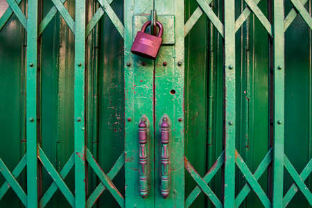 Closed green steel door stretch with locked golden keyの写真素材