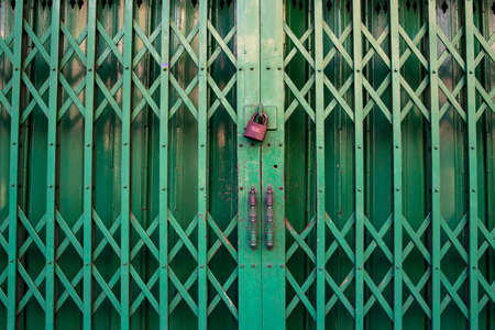 Closed green steel door stretch with locked golden keyの写真素材