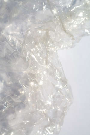 Abstract crumpled transparent plastic bag texture on white background, Close up & Macro shot, Selective focus, Light & Shadow, Recycle conceptの写真素材