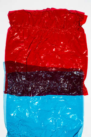 Thin sheet of multi coloured cellophane with shiny crumpled surface texture on white background, Abstract, Light & Shadow conceptの写真素材