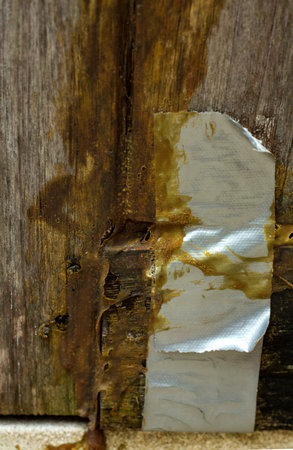 Damaged wooden door, Wooden door repaired by glue and gray adhesive tape, Close up & Macro shot,...