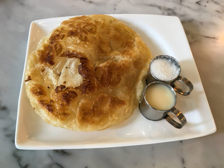 Roti, Kind of indian food made of flour on white plate with sugar stainless cup, milk stainless cup, Marble backgroundの写真素材