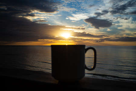 Silhouette blurred coffee cup at sunrise background, Close up shotの写真素材