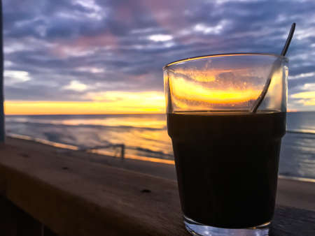 Silhouette glass of coffee with spoon at sunrise background, Close up shotの写真素材
