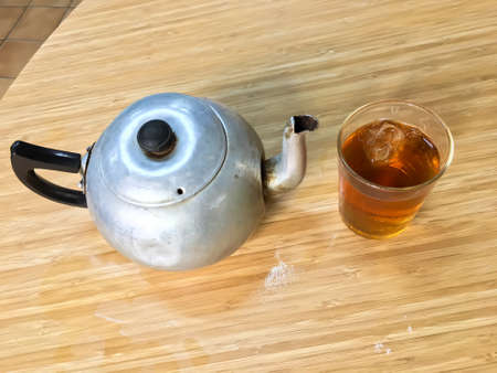 Glass of ice Chinese tea with teapot on wooden tableの写真素材