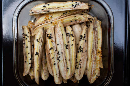 Baked Cultivated Banana with black sesame seeds, Sesamum indicum in the  glass bowl, On black stainless steel tray, Close up & Macro shot, Healthy food conceptの写真素材