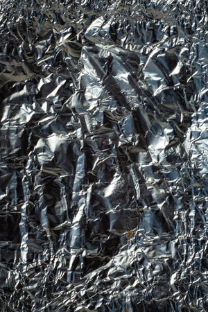 Blurred thin sheet of Silver foil with shiny crumpled surface texture background