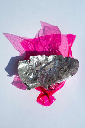 Thin sheet of pink colour cellophane and Silver foil  with shiny crumpled surface texture  on white background, Abstract, Light & Shadow conceptの写真素材
