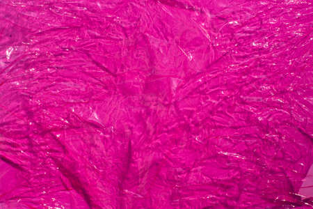 Thin sheet of pink colour cellophane with shiny crumpled surface texture , Abstract background, Light & Shadow conceptの写真素材