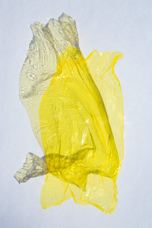 Thin sheet of yellow colour cellophane with shiny crumpled surface texture  on white background, Abstract, Light & Shadow conceptの写真素材