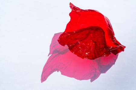 Thin sheet of red colour cellophane with shiny crumpled surface texture  on white background, Abstract, Light & Shadow conceptの写真素材