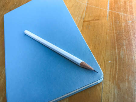 Notebook with white pencil on wood background, Close upの写真素材