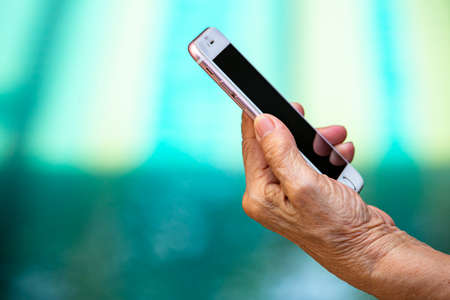 Bangkok Thailand - July 15, 2019 :  Senior woman's hand using iPhone 6s Pink in blue swimming pool background, Technology, Business concept, iPhone 6s pink was created and developed by the Apple inc.のeditorial素材