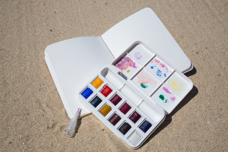 Notebook & Watercolor box on beach backgroundの写真素材
