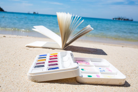 Notebook & Watercolor box on beach backgroundの写真素材