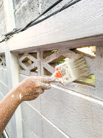 Woman's hand using paintbrush with white paint on wall, Stained  handの写真素材