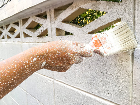 Woman's hand using paintbrush with white paint on wall, Stained  handの写真素材