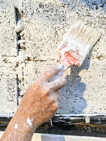 Woman's hand using paintbrush with white paint on wall, Stained  handの写真素材
