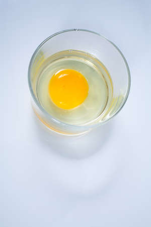 Raw chicken egg in glass bowl isolated on white backgroundの写真素材