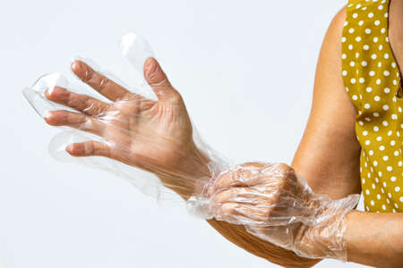 Senior woman's hands wearing disposable protective plastic glove on grey background, Close up shot, Prevention from covid19, Coronavirus, Bacteria, Healthcareの写真素材