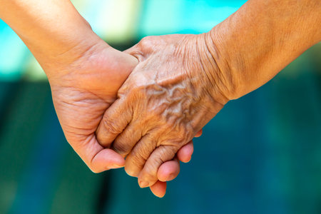 Hand in Hand, Mother holding hand of her daughter on bokeh blue swimming pool background, Asian body...