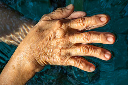 Senior woman's hands washing her hands in step 1 in bokeh blue pool  background, Close up & Macro shot, Selective focus, Prevention from covid19, Bacteria, healthcare concept, 7 step wash handの写真素材