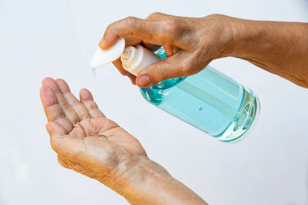 Senior woman's hands is pressing a bottle of sanitizer gel pump dispenser to wash her hands. Close up & Macro shot, Selective focus, Prevention from covid19, Bacteria, healthcare concept, 7 step wash handの写真素材