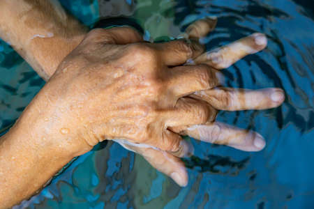Senior woman's hands washing her hands in step 3 in bokeh blue pool  background, Close up & Macro shot, Selective focus, Prevention from covid19, Bacteria, healthcare concept, 7 step wash handの写真素材