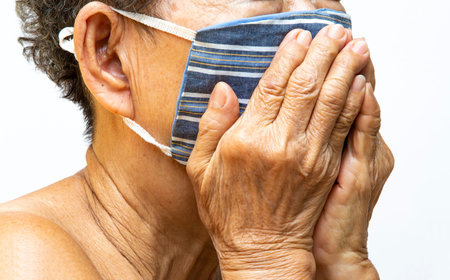 Senior woman wearing DIY handmade striped cloth face mask, Medical mask, Surgical mask, Two hands...