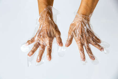 Senior woman's hands wearing disposable protective plastic glove on grey background, Close up shot, Prevention from covid19, Coronavirus, Bacteria, Healthcareの写真素材
