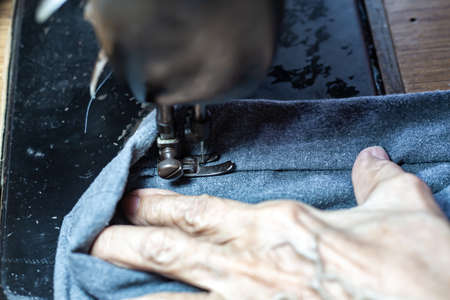 Senior woman's stitching grey fabric on vintage sewing machine, Thread, Needle, Close up shot, Selective focus, Sewing process, Female's hobby. Tailor conceptの写真素材