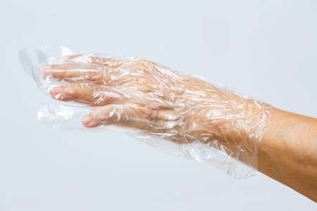 Senior woman's hands wearing disposable protective plastic glove on grey background, Close up shot, Prevention from covid19, Coronavirus, Bacteria, Healthcareの写真素材